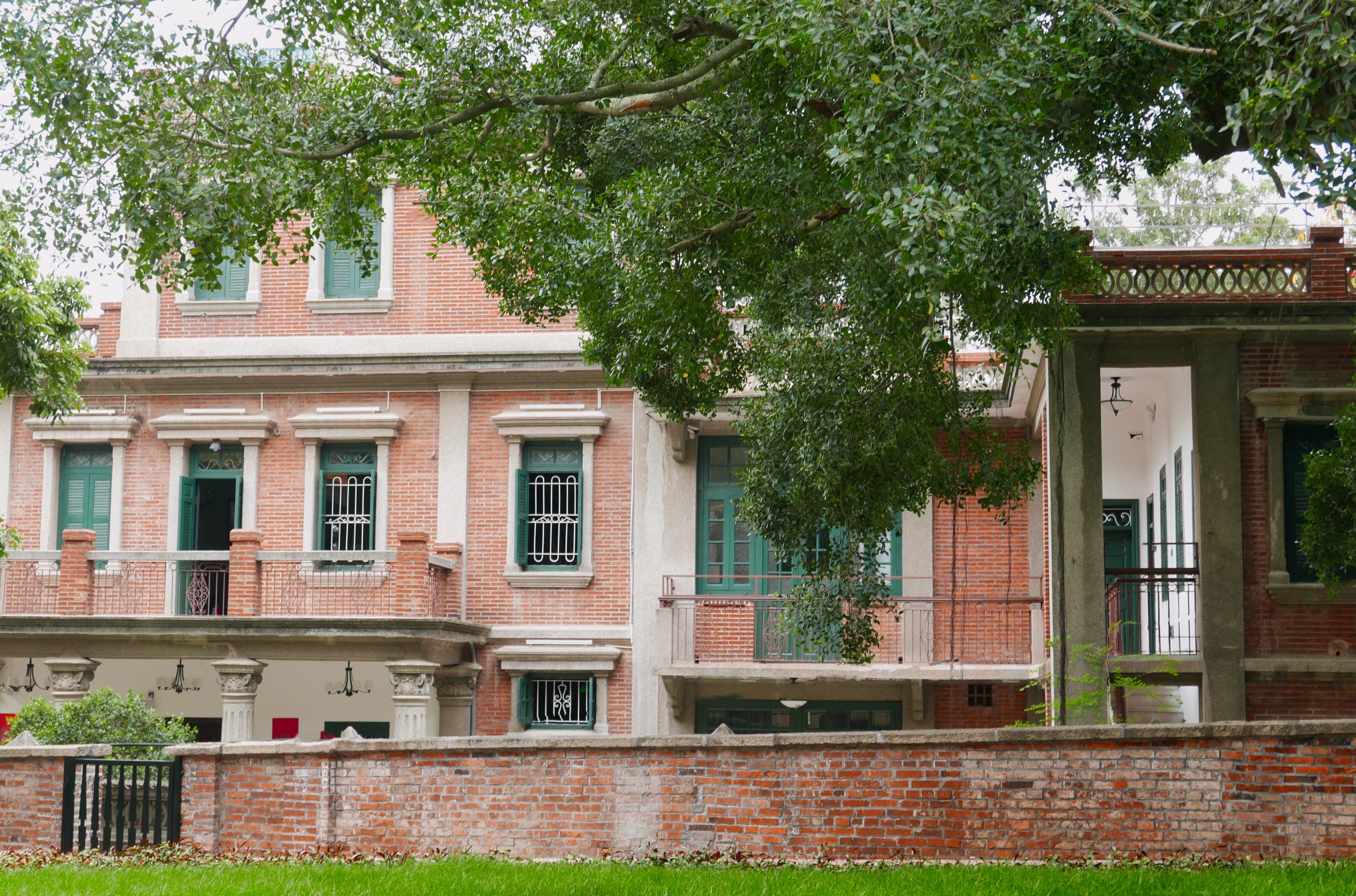 Red brick mansion covered by green leaves